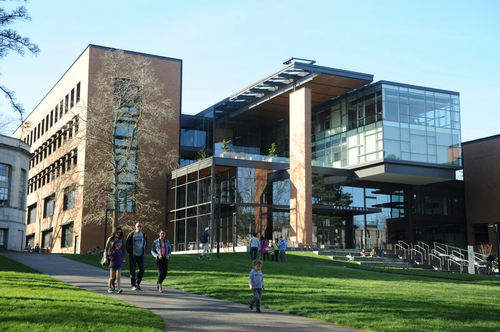 Estudiantes de universidad caminando por un campus moderno con edificios académicos al fondo
